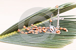 Closeup Catholic rosary with crucifix and beads on palm leaf