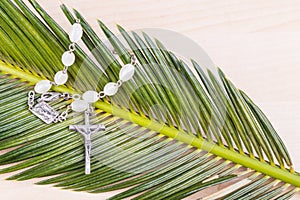 Closeup Catholic rosary with crucifix and beads on palm leaf