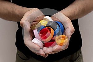 Closeup at caucasian hands full of colorful plastic bottle cups,