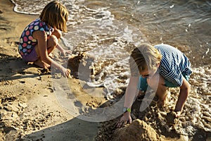 Closeup of caucasian kids playing with the sand together at the