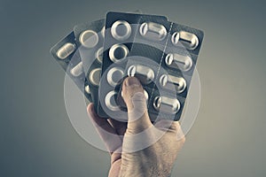 Closeup of Caucasian male hand holding many pill packaging foils