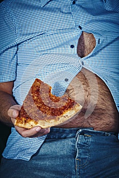 Man with a beer belly eating pizza photo