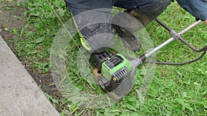 Closeup of caucasian man priming green lawnmower and getting ready to mow the lawn. Male hand starting a lawn mower. A