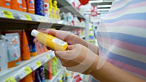 Closeup caucasian woman near shop shelves choosing cosmetics in market