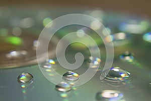 Closeup of a CD with water drops on it on the table under the lights with a blurry background