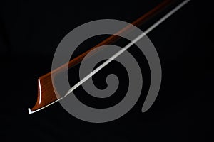Closeup of cello bow with black background.