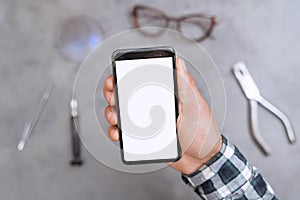 Closeup of cellphone with blank screen in man`s hand in optical workshop