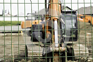 Closeup of chain-link fences with a construction truck in the dirt on the blurry background