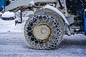 Closeup of a chained wheel of a snowy snow plow .