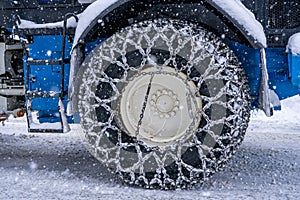 Closeup of a chained wheel of a snowy snow plow on the mountain ski resort in french Alps