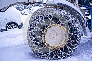 Closeup of a chained wheel of a snowy snow plow on the mountain ski resort in french Alps