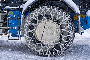 Closeup of a chained wheel of a snowy snow plow on the mountain ski resort in french Alps