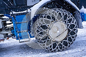Closeup of a chained wheel of a snowy snow plow on the mountain ski resort in french Alps