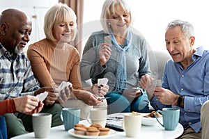 Closeup of cheerful elderly people chilling together, playing cards