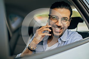 Closeup of cheerful man sitting in taxi, talking on phone