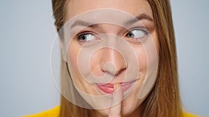 Closeup cheerful woman showing silence sign in studio camera on grey background.