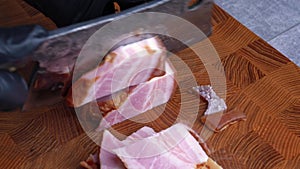 Closeup of chef cuts bacon guanciale into little cubes with old retro knife on wooden cutting board