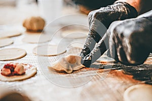 Closeup of chef hands in black gloves designing dumplings to put in the oven