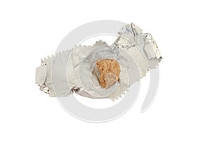 Closeup of a chewed gum on a crumpled foil bubblegum packaging isolated on white background