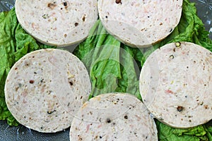 Closeup of chicken salami on lettuce leaves