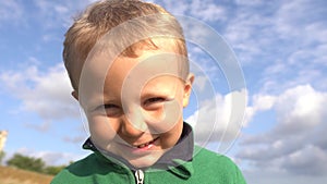 Closeup, child boy smiling and grimacing. Real emotions, boy on a sky background