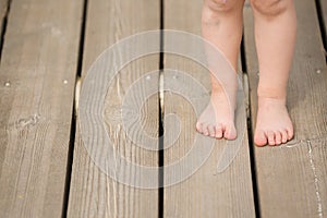 Closeup of child`s bare feet on wooden floor. Toddler`s legs and foot