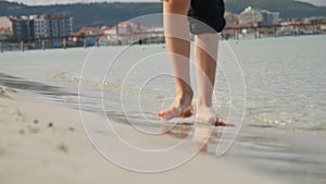Closeup of child's feet walking on the warm soft sand at sea beach. Concept of tourism, travel, summer vacation