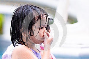 Closeup of child is squeezing the area of her nose to expel water from her nose.
