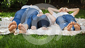 Closeup of children and mothers feet lying on grass in park or garden. Parenting, family, children development, and fun