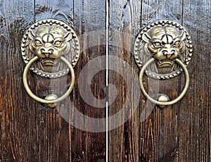 Closeup of Chinese lion door knockers on a wooden door