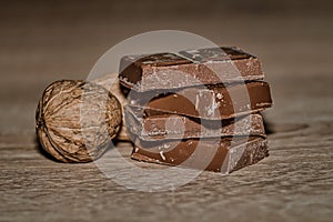 Closeup of chocolate bards and dry walnuts on a wooden surface