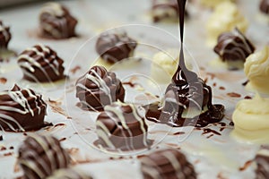 closeup of chocolate being drizzled on confections