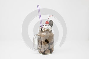 Closeup of a chocolate milkshake with whipped cream and an Oreo on top in a mason jar