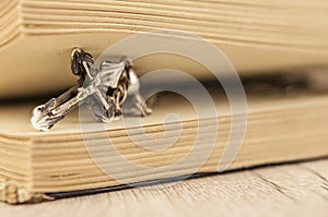 Closeup of Christian cross with silver chain on blank open book with a black wooden background