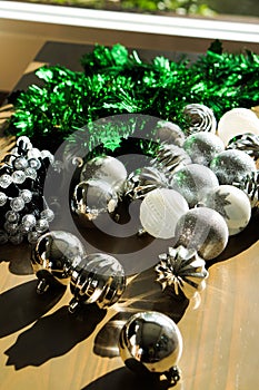 Closeup Christmas tree branch decorated with silver balls and white decor on the table