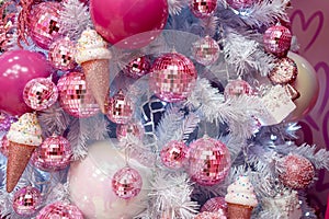 Closeup of Christmas tree decorated with pink shiny balls and icecreams