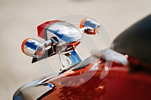 Closeup chrome detail and taillight and turn signals of orange retro vintage scooter.