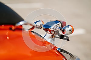 Closeup chrome detail and taillight and turn signals of orange retro vintage scooter.
