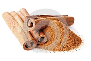 Closeup of cinnamon sticks and powder of ground cinnamon on white