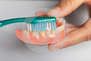 Closeup cleaning dental prothesis with toothbrush