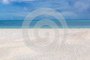 Closeup of clear beach sand, blur sea and sky. Peaceful tropical beach landscape. White sand, blue sky. Beach nature concept