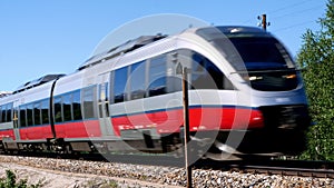 Closeup clip of two red and gray passenger train cars passing by quickly on the railroad track.