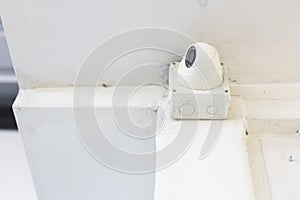 Closeup of closed circuit television camera or CCTV and box control on white concrete ceiling