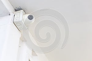 Closeup of closed circuit television camera or CCTV and box control on white concrete ceiling