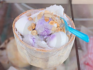 Closeup of coconut milk ice-cream in coconut shell strew with ground nut