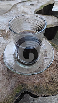 Closeup of a coffee cup containing black coffee on an abstract wooden table.