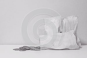 Closeup coin with old white money bag on the table and wallpaper in room textured background in black and white tone with copy spa