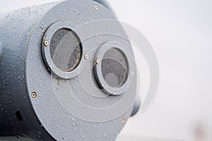 Closeup coin operated binoculars overlooking after rain