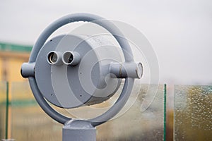Closeup coin operated binoculars overlooking after rain