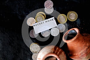 Closeup of coins and clay jugs with a small piece of paper with a message.